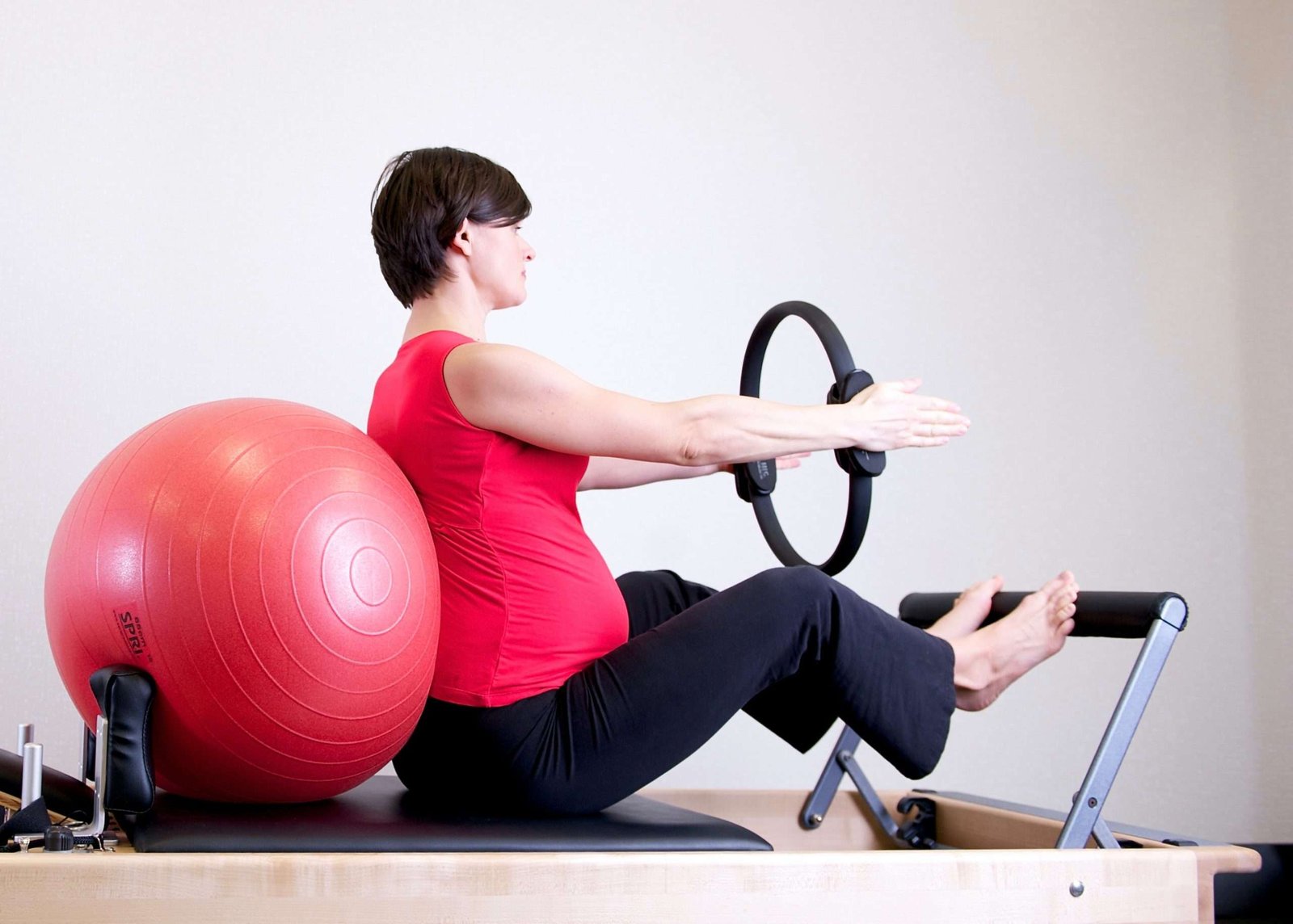 a pregnant woman exercising on a pilates machine
