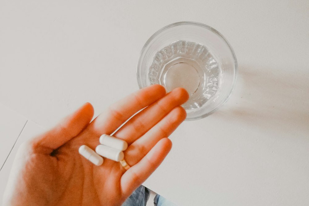 Person holding a single white medication pill